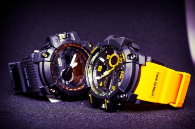 Elektronik modern kuvars sporu. Siyah arka planda lastik kayışı olan dijital sarı ve siyah kol saati..