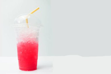 Beyaz masadaki plastik bardakta buzlu meşrubat. Kırmızı su, limonlu soda, berrak plastik bardaktaki buz içme suyu, yaz teknisyenlerindeki susuzluğu ve tazeliği gidermeye yardımcı oluyor. Beyaz zemini yerleştir. Seçmeli odak