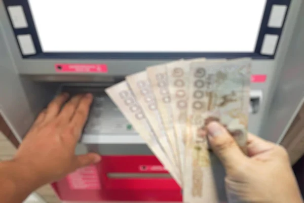Blurred Close up withdraw bank notes in the hand of five thousand baht from the ATM.unemployment benefits after filing a claim concept.