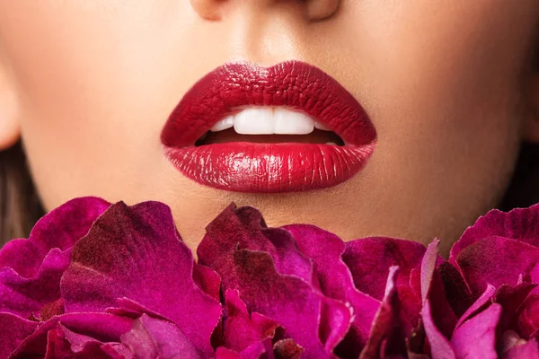 Lips make-up. Beauty high fashion trendy red colour lips makeup sample, sexy mouth closeup. Red Lipstick. Professional Make up artist work with flowers.
