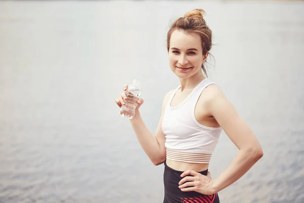 Sporty woman drinking water from a bottle. Beautiful fit Girl. Fitness model outdoors. Weight Loss. Healthy lifestyle. Sporty healthy female.