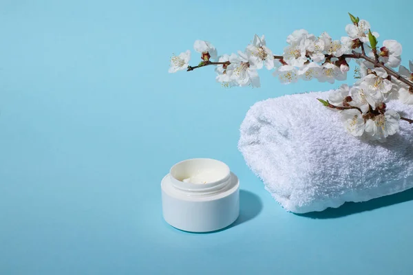 Beautiful Spa and wellness composition with natural flower blossom, creme and towel on pink background. Natural beauty product concept.