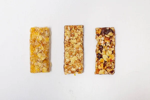 Granola bar top view. Healthy organic sweet dessert snack. Cereal granola bar with nuts, fruit and berries on white wooden table