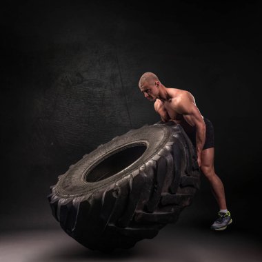 Ağır tekerleği kaldıran sporcu