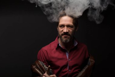 Siyah arka planda hareket eden karizmatik bir adam. Duman kafamdan geliyor. Deri kahverengi ceket ve kırmızı gömlek.