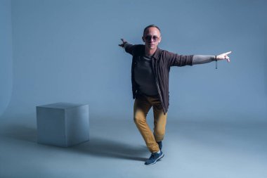 Erkekler için model testleri. Dansın dinamiklerinde olan bir adamın şık fotoğrafları. Özgüveni, özgürlüğü, hafifliği ve esnekliği ifade eder. Beyaz küpün yanındaki adam.