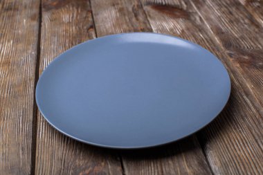 Ahşap bir yüzeyde boş mavi bir tabak..