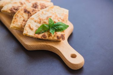 Patatesli tortilla, pide, chapati, fesleğen yaprağı ile süslenmiş, siyah arka planda, doğu yemekleri.
