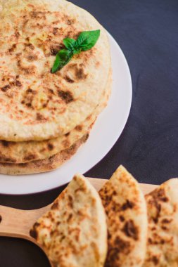 Patatesli tortilla, pide, chapati, fesleğen yaprağı ile süslenmiş, siyah arka planda, doğu yemekleri.