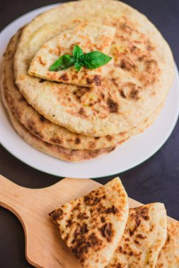 Patatesli tortilla, pide, chapati, fesleğen yaprağı ile süslenmiş, siyah arka planda, doğu yemekleri.