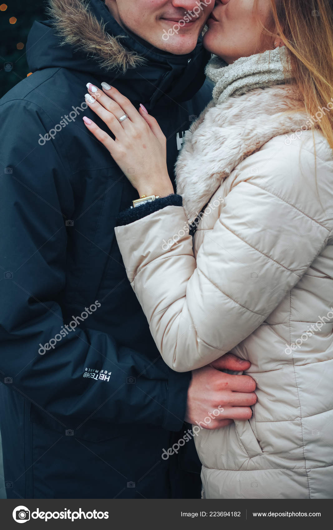 美丽的年轻夫妇在寒冷的冬夜享受着他们站在街上看圣诞树上的装饰品背景是五彩斑斓的街灯新年主题 图库照片 C Avelina B