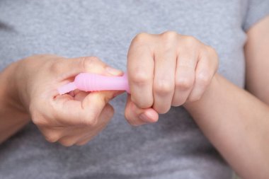 Kadınların el katlama regl bardağını kapatarak nasıl kullanılacağını göster. Kadın sağlığı konsepti, sıfır atık alternatif
