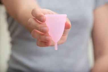 Genç kadın elleri aybaşı fincanı ve küçük bir çanta tutuyor. Aybaşı kadehi kadınların elinde.