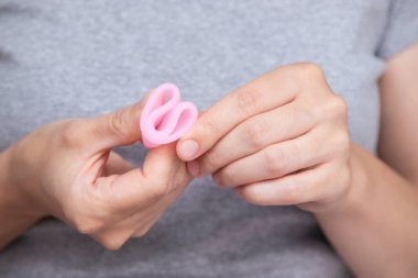 Kadınların el katlama regl bardağını kapatarak nasıl kullanılacağını göster. Kadın sağlığı konsepti, sıfır atık alternatif