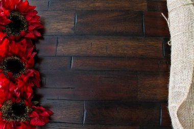 Ahşap arka plan çerçeveli haddelenmiş çuval bezi kumaş ve bir çiçek.