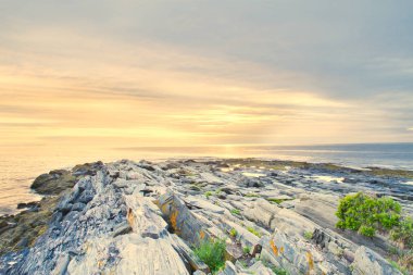 Maine kayalık sahil kapalı bulutlar arkasında yükselen güneş.