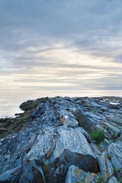 Maine kayalık sahil kapalı bulutlar arkasında yükselen güneş.