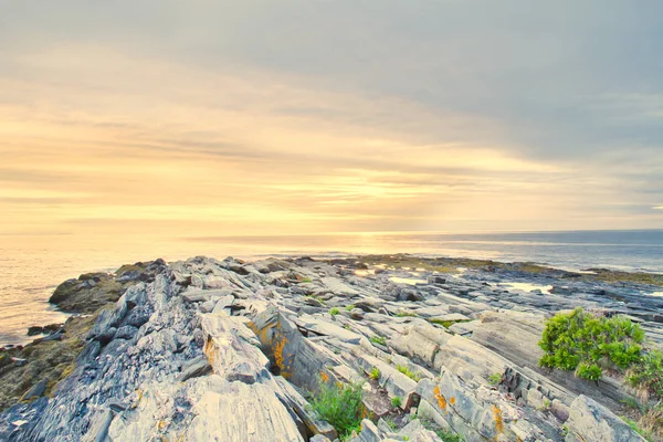 Maine kayalık sahil kapalı bulutlar arkasında yükselen güneş.