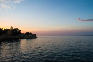 Güneş ayarı Atlantik Okyanusu üzerinden ve arkasında bir sur Cadiz, İspanya.