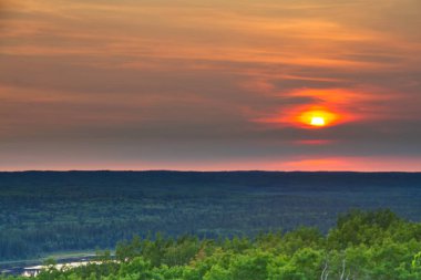 The sun setting over the forest of Prince Albert National Park. clipart