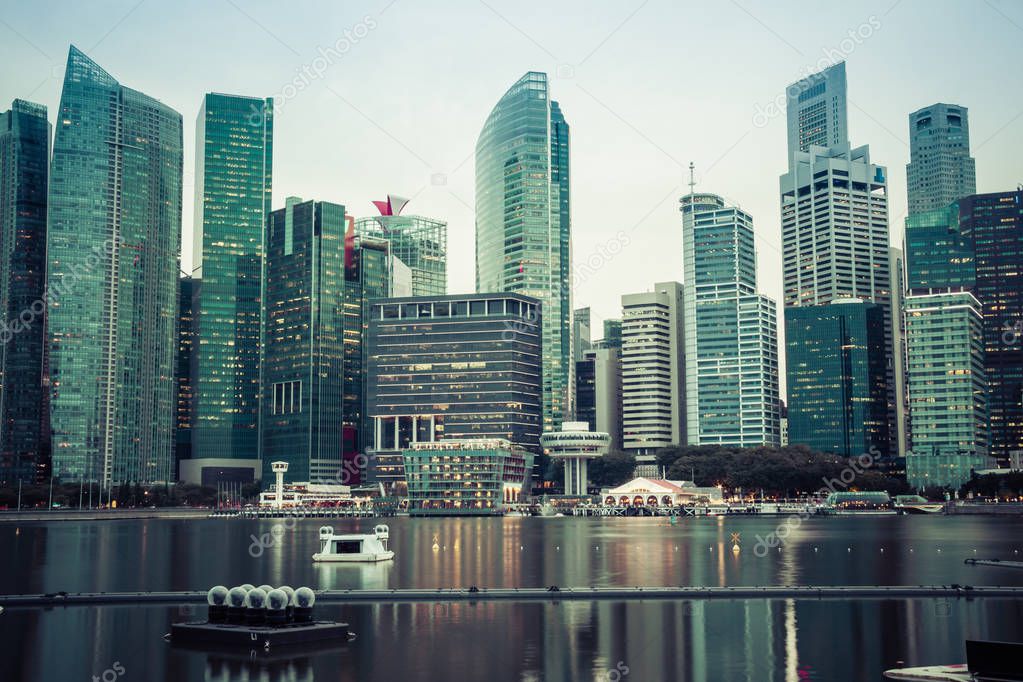 The skyline of Singaproe in the evening as seen from Marina Bay featuring modern office buildings.