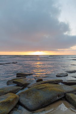 Kaliforniya kıyısındaki kayalık bir sahilden gün batımı.