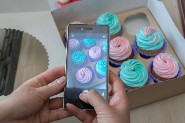 Kadınların elleri tarafından bir kutu bir telefon ile cupcakes ile fotoğraf çekimi