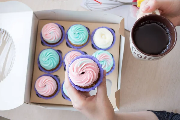 pembe ve mavi bir kutu cupcakes arka plan üzerinde bir kızın elinde krem ile Cupcake