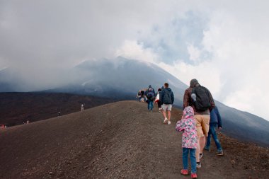 Turistler yanardağ krater arasında yürümek. Üstündeki bulutlarda Etna Yanardağı. Sicilya, İtalya. 