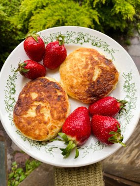 Tabağında çilek olan Rus şurubu. Yaz kahvaltısı. Kızarmış peynirli krep. kaymak. 