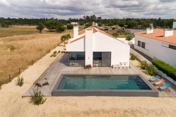 Bahçe havuzu ve ahşap güvertesi olan modern bir ev.