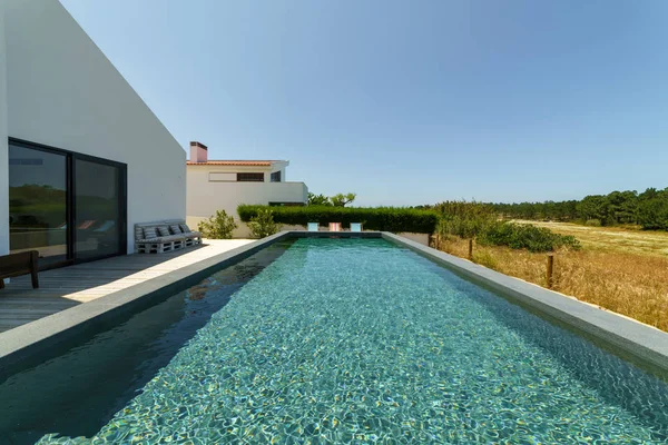 Bahçe havuzu ve ahşap güvertesi olan modern bir ev.