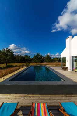 Bahçe havuzu ve ahşap güvertesi olan modern bir ev.