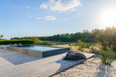 Bahçe havuzu ve ahşap güvertesi olan modern bir ev.