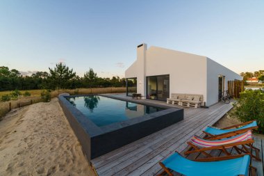 Bahçe havuzu ve ahşap güvertesi olan modern bir ev.