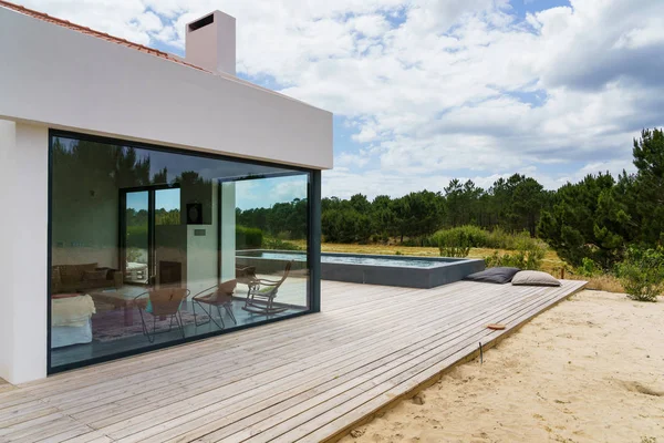 Bahçe havuzu ve ahşap güvertesi olan modern bir ev.