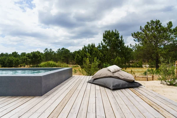 Bahçe havuzu ve ahşap güvertesi olan modern bir ev.