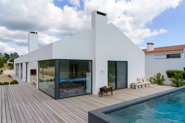 Bahçe havuzu ve ahşap güvertesi olan modern bir ev.