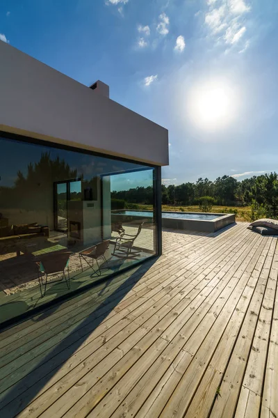 Bahçe havuzu ve ahşap güvertesi olan modern bir ev.