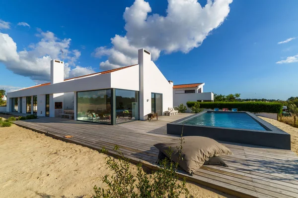 Bahçe havuzu ve ahşap güvertesi olan modern bir ev.