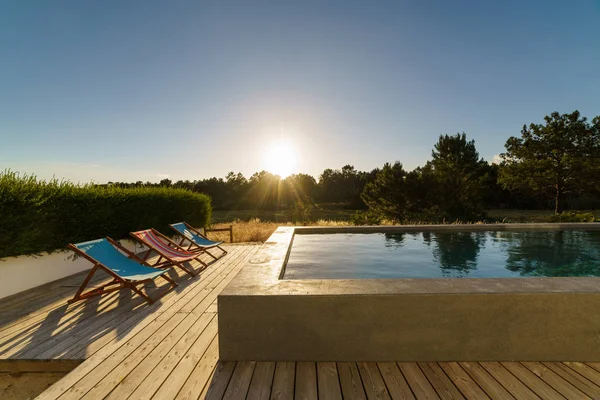 Bahçe havuzu ve ahşap güvertesi olan modern bir ev.