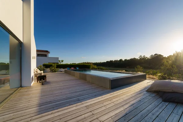 Bahçe havuzu ve ahşap güvertesi olan modern bir ev.