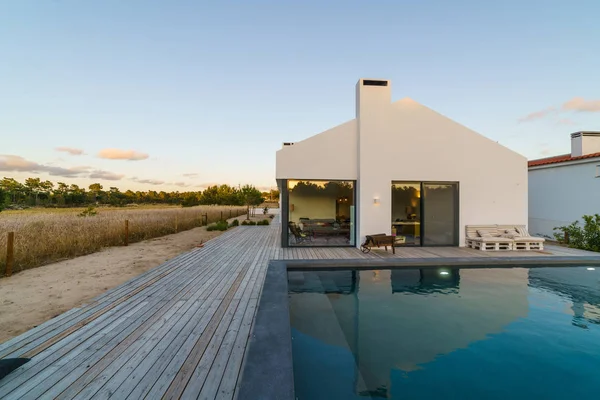 Bahçe havuzu ve ahşap güvertesi olan modern bir ev.