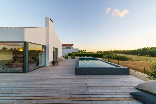 Bahçe havuzu ve ahşap güvertesi olan modern bir ev.