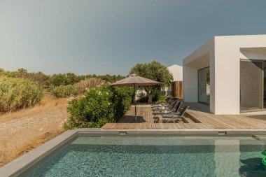 Bahçe havuzu ve ahşap güvertesi olan modern bir ev.