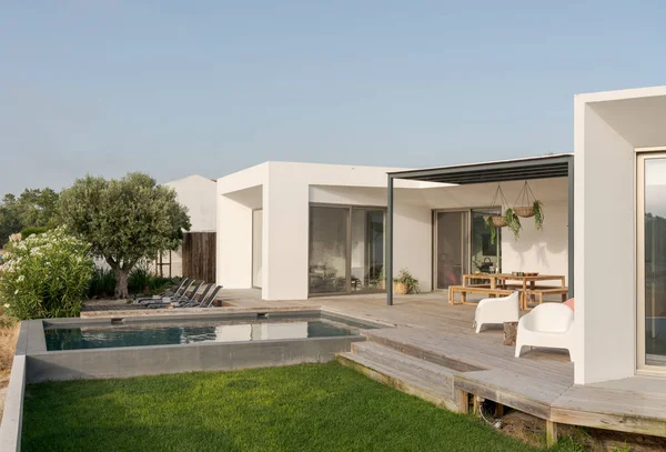 Bahçe havuzu ve ahşap güvertesi olan modern bir ev.