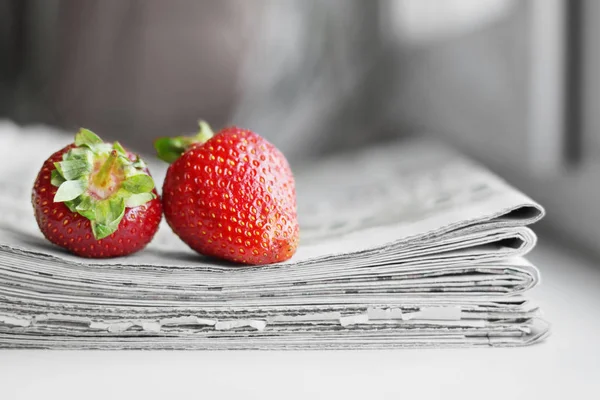 Stack of newspapers and strawberries. Daily journals with headlines and articles and fresh fruits. Concept for juicy news