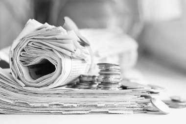 Gazeteler ve para yığını. Günlük gazete haberleri ile katlanmış ve haddelenmiş sikkeler üzerinde tablo yığını. Dergi ve değişikliği, yan görünümü çok  