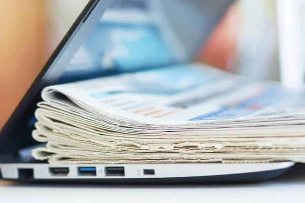 Gazete ve dizüstü bilgisayar. Haber ile tabloid dergi üstünde özel bilgisayar yığını. İki farklı bilgi kaynaklarını   