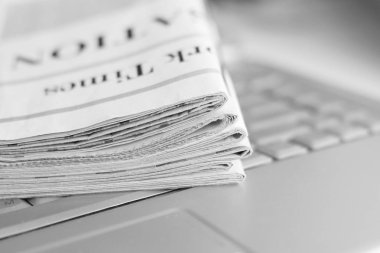 Gazete ve dizüstü bilgisayar. Bilgisayar haberleri ile günlük gazeteleri yığını. Sayfa başlıkları, makaleler ile katlanmış ve elektronik cihaz tuş takımında yığılmış. Modern araç ve eski dergiler, kağıt üzerinde odaklanmak 